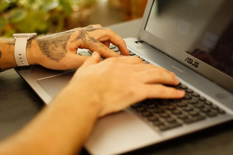 Close-up of a person typing on a laptop keyboard.